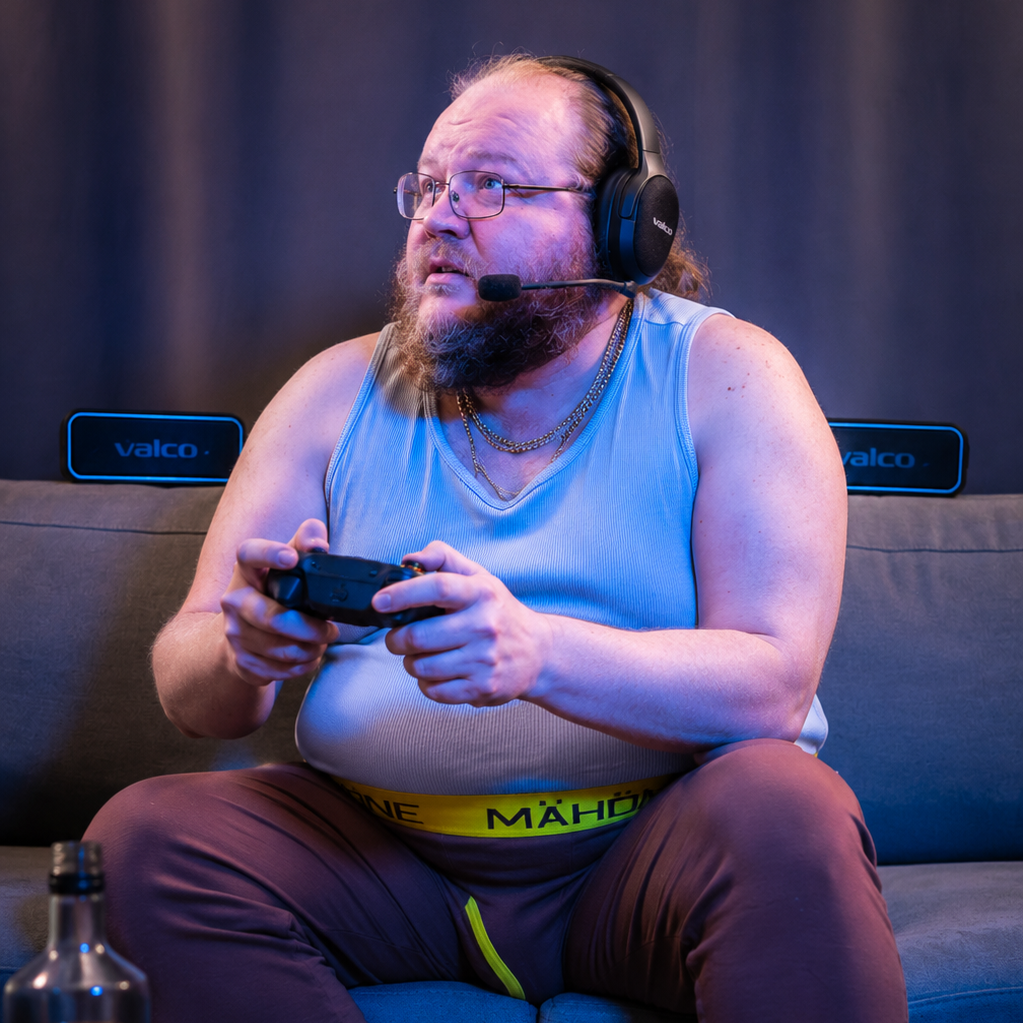 Mies pelaa konsolia sohvalla Valco-headset päässä